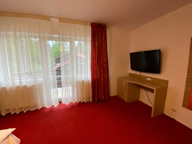 Dormitor cu TV, birou și ușă spre balcon