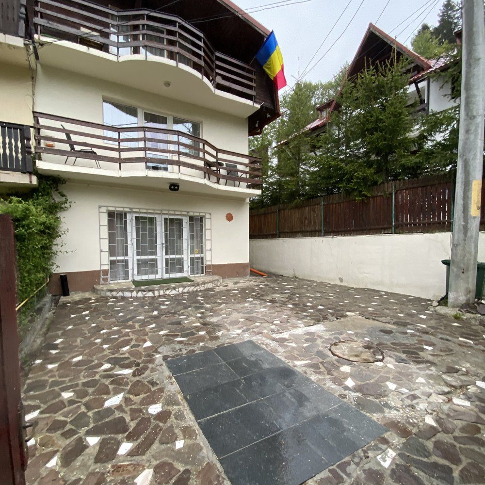 Intrarea Vila Amira Predeal — fațadă albă, balcoane și steagul României