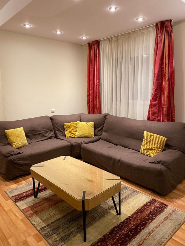 Colțul de relaxare din living — canapea pe colț, măsuță de lemn și covor